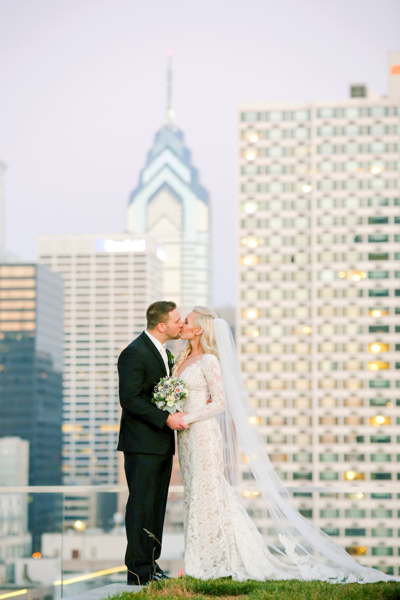 Bride and groom kissing on Cira Green with the Philadelphia skyline behind them