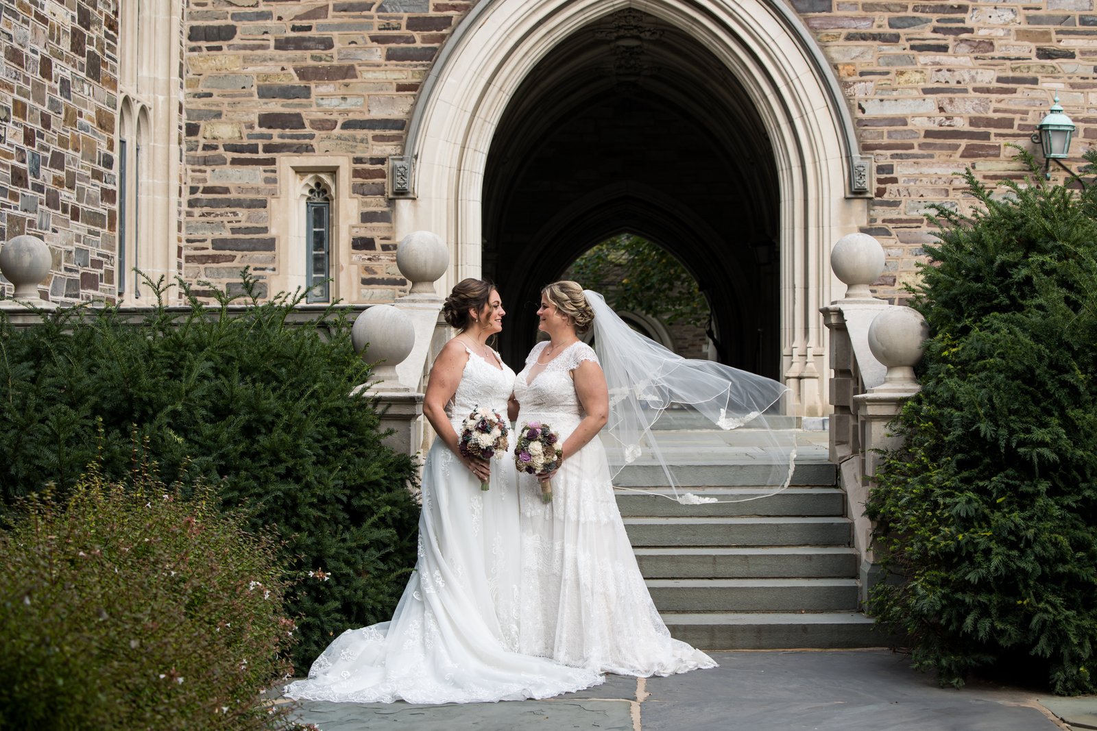 Two brides outside a stone archway in Princeton, New Jersey