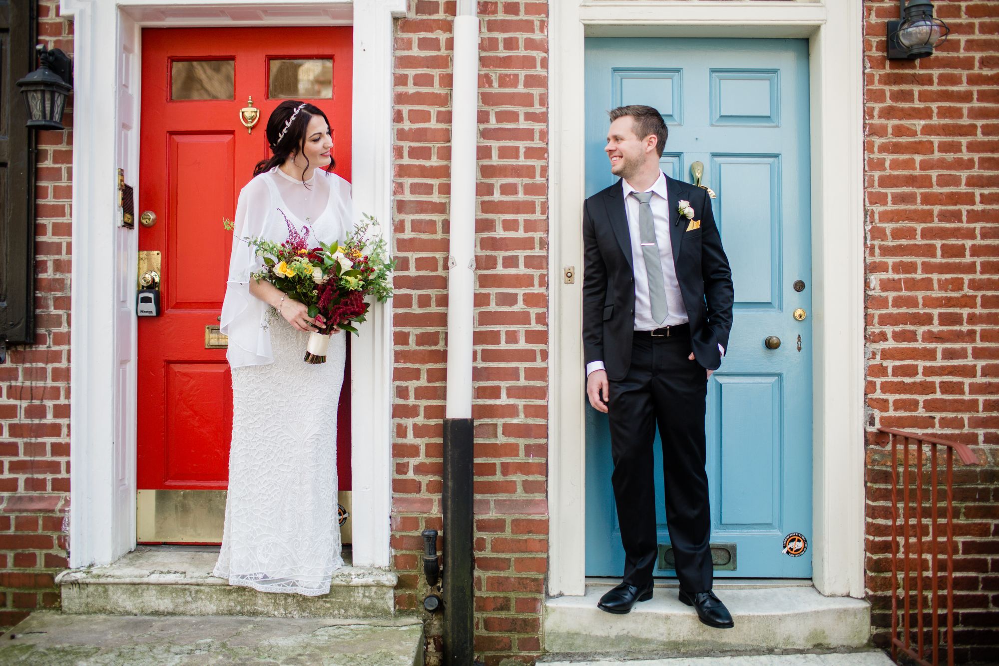 Bride and groom in adjoining doorways on a brick Old City street in Philadelphia