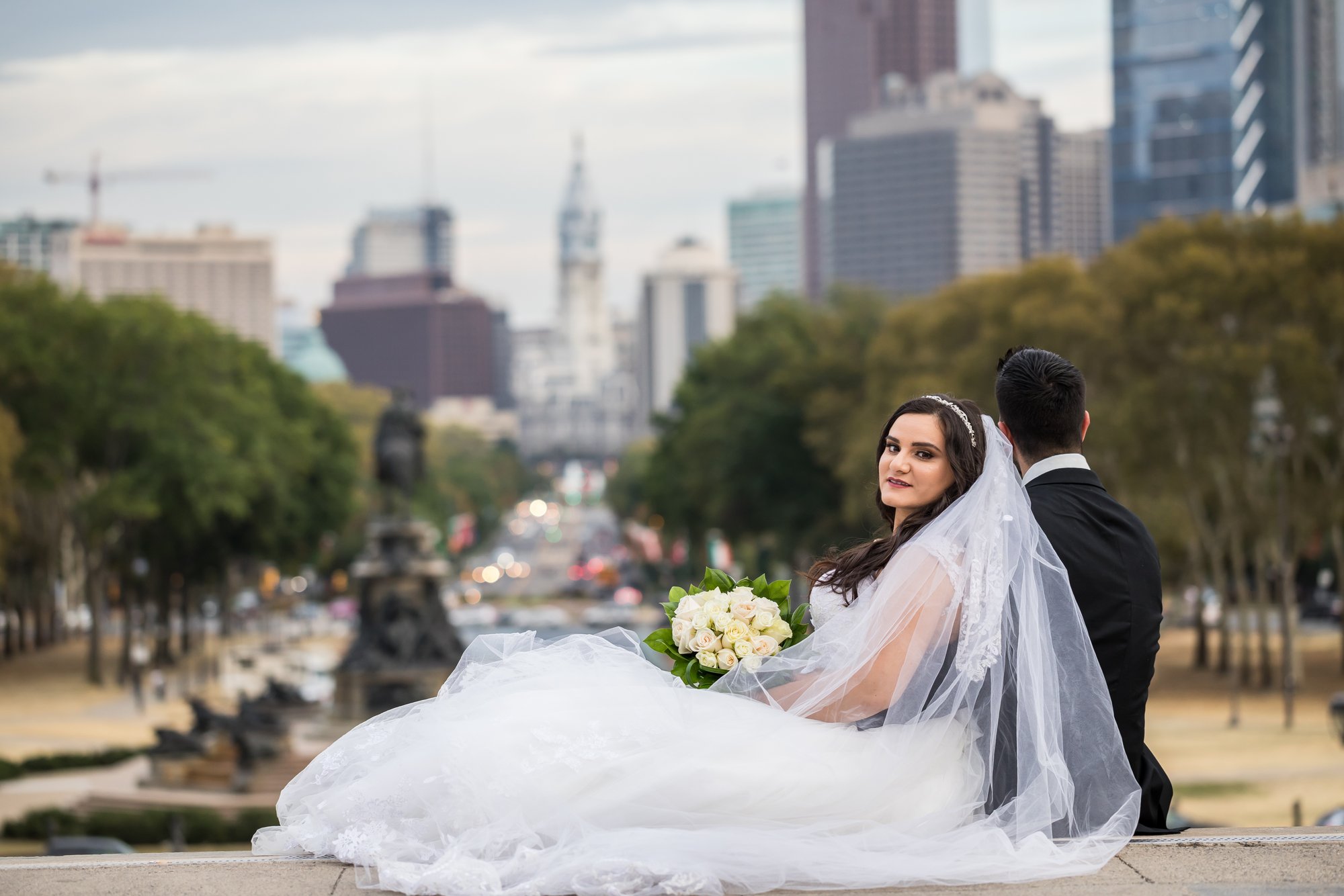Bride and groom on the Art Museum terrace looking down the Benjamin Franklin Parkway toward Philadelphia City Hall